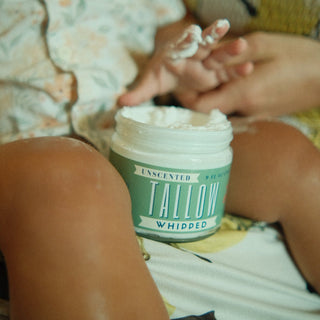 Person holding a jar of Tallow Whipped cream with another person's hand in the background.