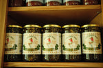 A row of The Lady May candied jalapenos 24oz jars on a wooden shelf, a gourmet traditional farm-to-table Southern pickled gift idea
