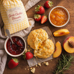 The Lady May Garlic Cheddar Biscuit close-up split open with strawberry and peach preserves and fresh fruit