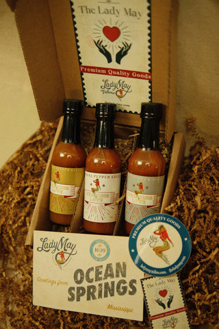 The Lady May Burning Love hot sauce trio gift box from Ocean Springs Mississippi with three pepper sauce bottles and greeting card, a gourmet small-batch farm-to-table Southern hot sauce gift set