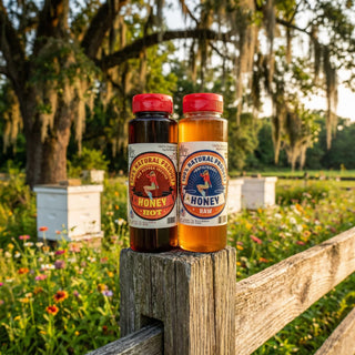 The Lady May raw and hot honey bottles on a fence post at a Southern apiary with beehives, wildflowers and oak trees, a traditional farm-to-table local honey with natural benefits