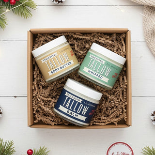 Three jars of tallow products in a box on a festive background with Christmas decorations.